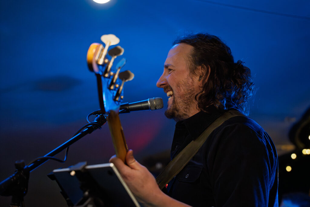 Charlie Evans playing bass at a gig. Learn bass with the local master!
